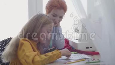 可爱的小女儿学习如何缝纫。 红头发的母亲向女孩展示如何选择<strong>衣服</strong>的<strong>纽扣</strong>